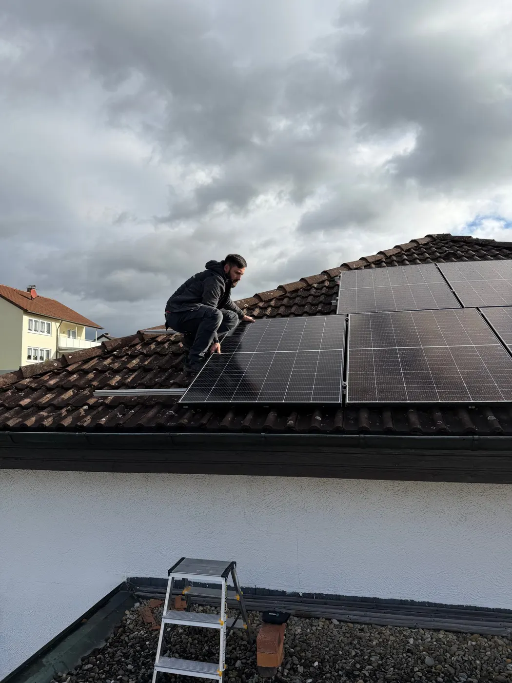 Monteur von SK-Elektrotechnik verlegt Solarmodule auf einem Ziegeldach